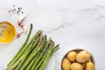 Green fresh asparagus with spices and potatoes on a white background