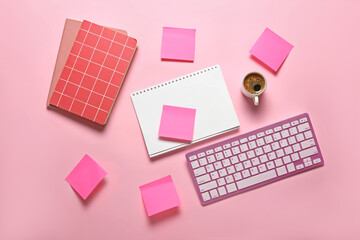 Notebooks, note papers, PC keyboard and cup of coffee on pink background