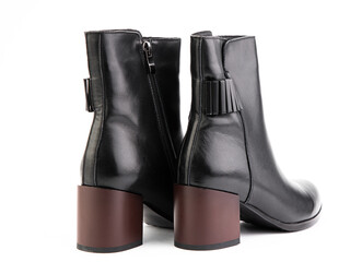 Women's autumn ankle black leather boots with red average heels, isolated white background. Back side view. Fashion shoes. Photoshoot for shoe shop