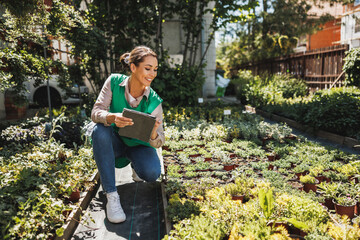 Florist Woman With Digital Tablet Care For Flowers In A Greenhouse