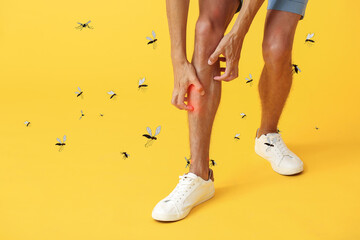 Young man scratching himself and many mosquitoes on yellow background - obrazy, fototapety, plakaty