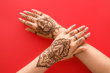 Female hands with beautiful henna tattoo on color background