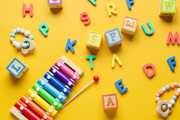 Children building blocks, letters and xylophone on yellow background