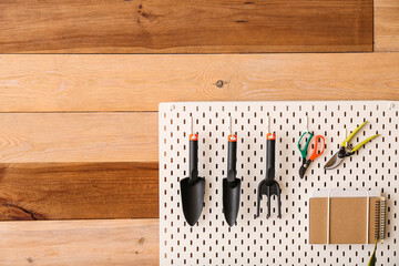 Pegboard with gardening tools on wooden wall