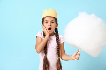 Cute little girl with cotton candy on blue background