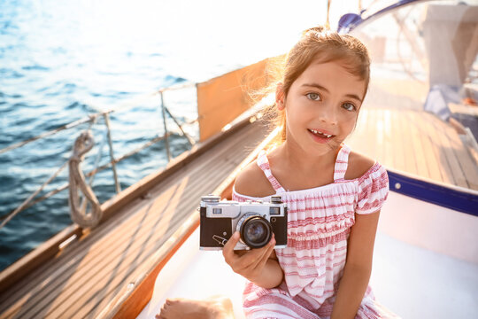 Cute little girl with photo camera resting on yacht