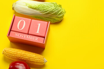 Vegetables and cube calendar with date NOVEMBER 1 on yellow background, closeup. World Vegan Day...