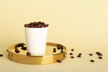 Takeaway paper cup with coffee beans on beige background