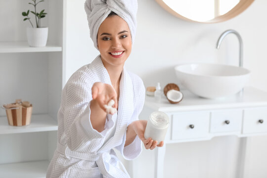 Young woman with jar of coconut oil in bathroom
