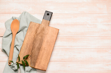 Cutting board and spoon on light wooden background