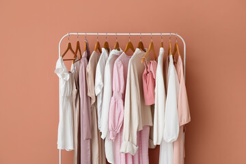 Rack with stylish female clothes near pink wall