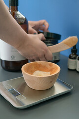 beautician mixes yellow color hair mask in wooden plate
