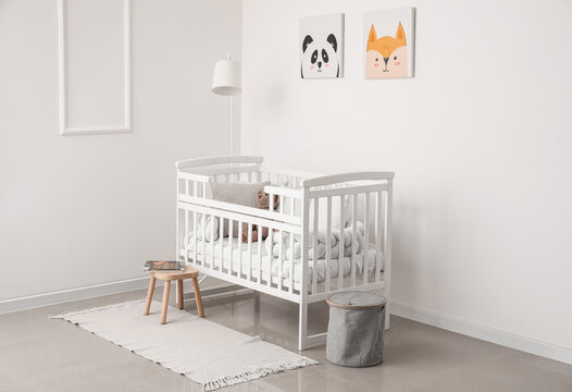 Interior of light nursery with baby crib, lamp and stool