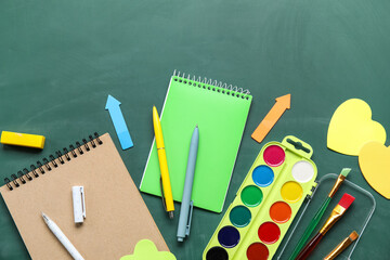 Stationery supplies with paints on school chalkboard