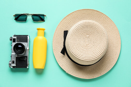 Sunscreen cream with photo camera, sunglasses and hat on blue background