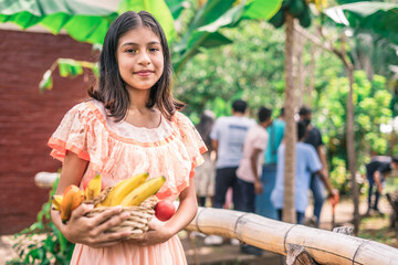Latin girl smiling and looking at the camera holding fruits in her hands during a harvest festival in Nicaragua
