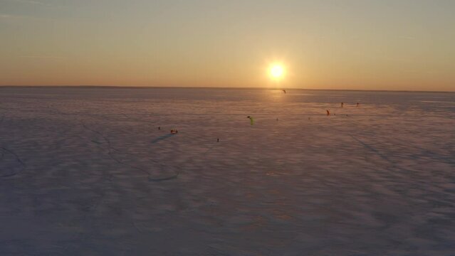 4k Aerial footage, sunset time on the Kiev Sea. A group of snow kiting enthusiasts doing their favorite thing. Colored parachutes develop against a sitting golden sun. Pleasant outdoor activities