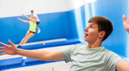 Closeup face of excited teenager bouncing on trampoline with other people in sports center ..