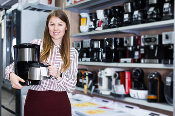 Smiling seller showing coffeemaker in domestic appliances section