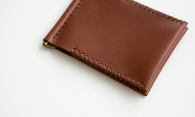 Orange men's money clip handmade leather wallet. Empty money clip wallet with a two pockets for cards lies on a white table. Selective focus, copy space.