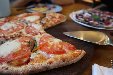 eating delicious Pizza Margherita on the wooden plate close-up with pizza cutter