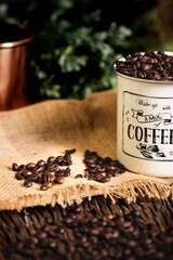 Coffee beans in white and bronze coffee cup on the old wood table. 