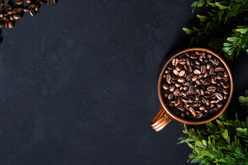 Roasted coffee beans in bronze coffee cup. Ground coffee in spoon. Dark gray background.
