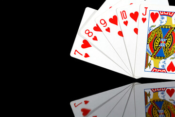 five playing cards of red suit on a dark background