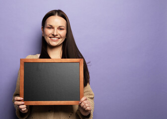 Young student woman holding a chalkboard isolated on purple background