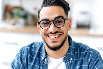 Close-up portrait of a handsome charismatic Arabian or Indian guy with glasses, freelancer or...
