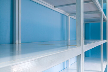 Empty white shelves in blue storage room