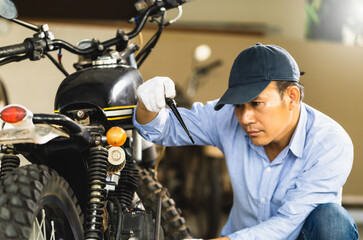 Man repairing motorcycle in repair shop, Mechanic fixing motorbike in workshop garage, Repairing and maintenance concepts