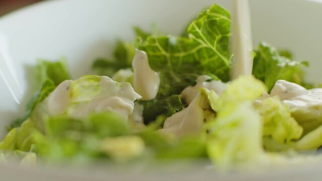 Pour dressing on a Caesar salad. Camera slider shot. 4K footage.