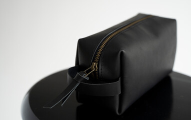 Man's black leather personal cosmetic bag or pouch for toiletry accessory on a black surface with...