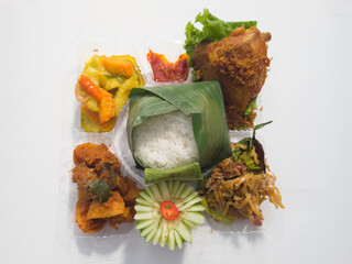 Mixed rice dishes filled with white rice, fried chicken, fried noodles, fried chili sauce with cucumber slices