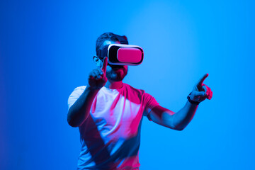 Vitrual reality concept. Man are playing a game in virtual reality. Young man in VR glasses are gaming with realistic holograms in simulator. Entertainment and leisure concept. Modern technologies.