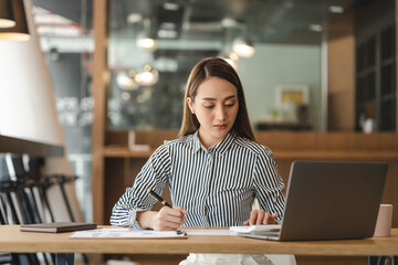 Fototapeta premium Beautiful young asian woman calculating expenses household and writing notebook on desk, girl checking bill.