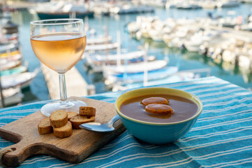 Homemade fish soup with croutons served with glass of cold rose wine and view on colorful...