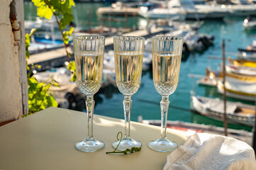 Three glasses of French champagne sparkling wine and view on colorful fisherman's boats in old harbour in Cassis, Provence, France
