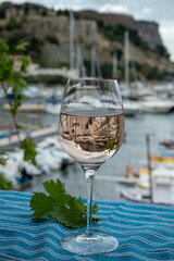 Rose wine in glass served on outdoor terrace with view on old fisherman's harbour with colourful boats in Cassis, Provence, France