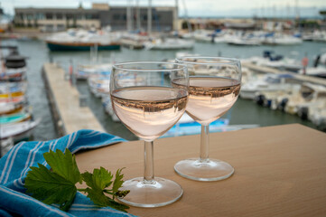 Rose wine in glasses served on outdoor terrace with view on old fisherman's harbour with colourful boats in Cassis, Provence, France