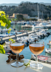 Cold rose wine in glasses served on outdoor terrace in sunlights with view on old fisherman's...
