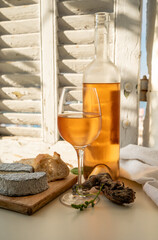 Cold rose wine in glass and bottle served with goat cheeses on outdoor terrace with view on old...