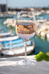 Rose wine in glass served on outdoor terrace with view on old fisherman's harbour with colourful boats in Cassis, Provence, France