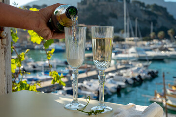 Fototapeta Pouring in two glasses of French champagne sparkling wine and view on colorful fisherman's boats in old harbour in Cassis, Provence, France obraz