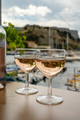 Rose wine in glasses served on outdoor terrace with view on old fisherman's harbour with colourful boats in Cassis, Provence, France
