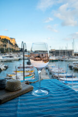 Rose wine in glass served with goat cheeses on outdoor terrace with view on old fisherman's harbour...