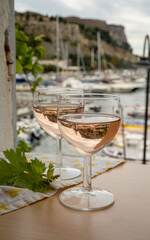 Rose wine in glasses served on outdoor terrace with view on old fisherman's harbour with colourful boats in Cassis, Provence, France