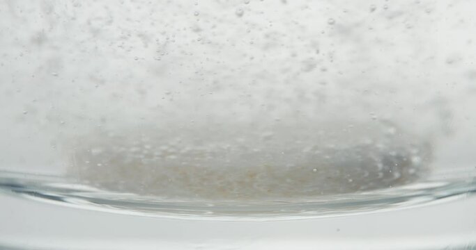Effervescent tablet fall dissolve glass of water in macro close up