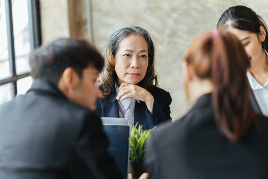 Asian business partners discussing documents and ideas at meeting, Successful business team sitting in office and planning work.